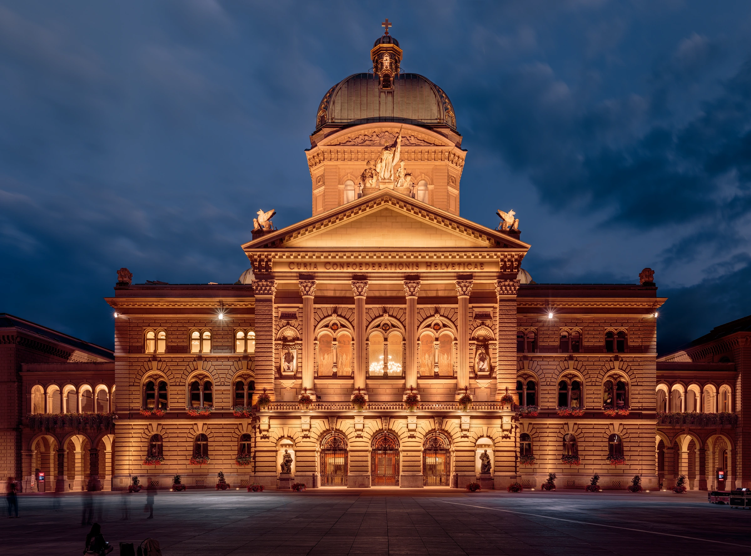 The illuminated Federal Palace in Bern beneath a dramatic blue-hour sky. Real stitched architectural photograph.