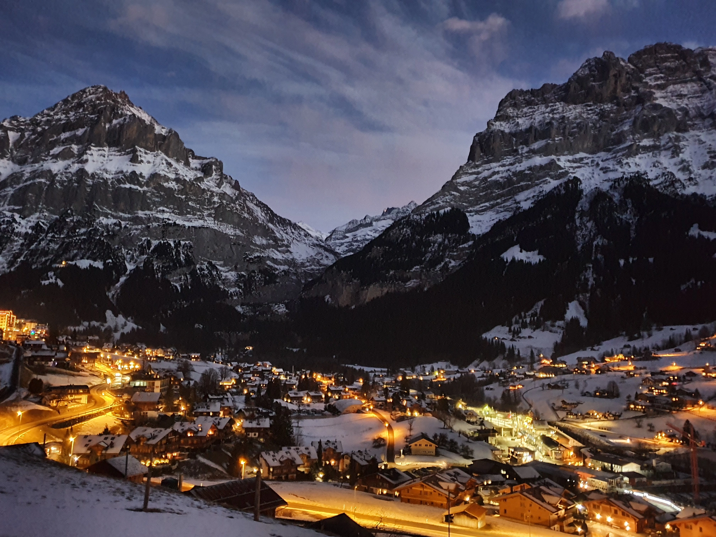 Grindelwald’s illuminated winter chalets below the Eiger and surrounding peaks at night.