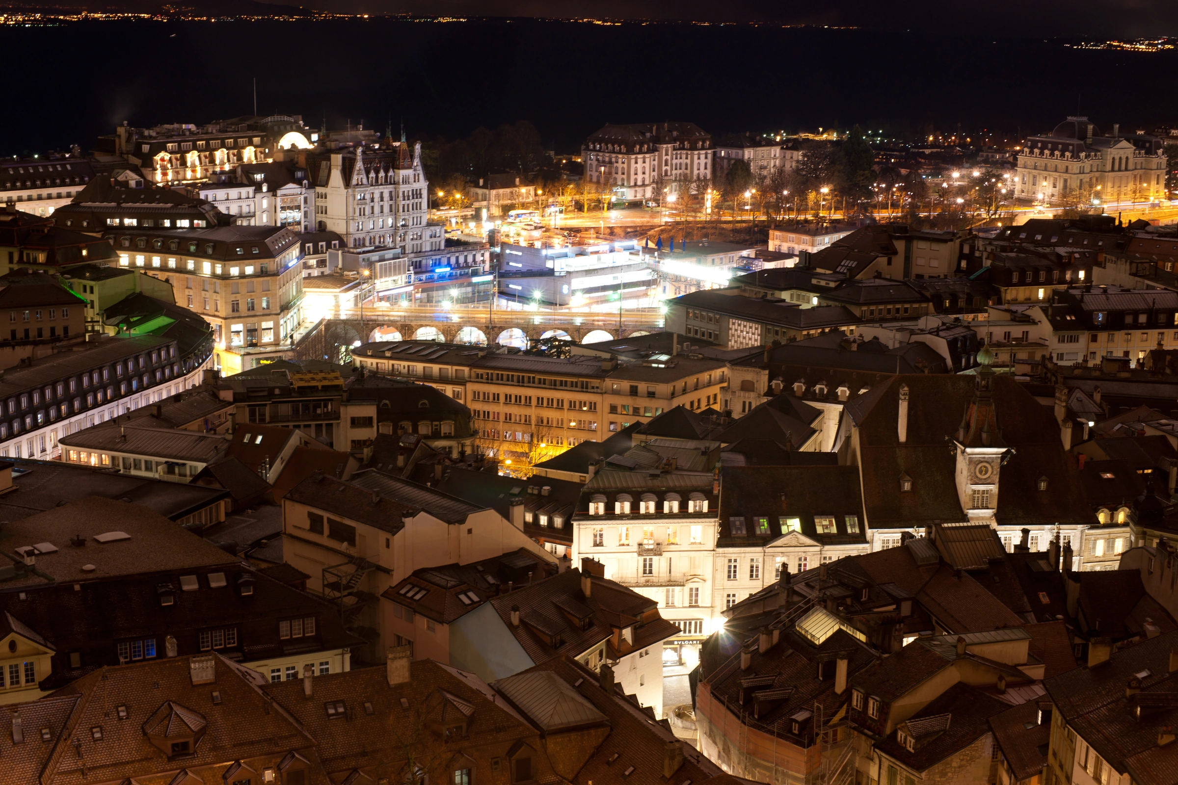 Lausanne at night from the cathedral, with illuminated historic rooftops and the Flon quarter.