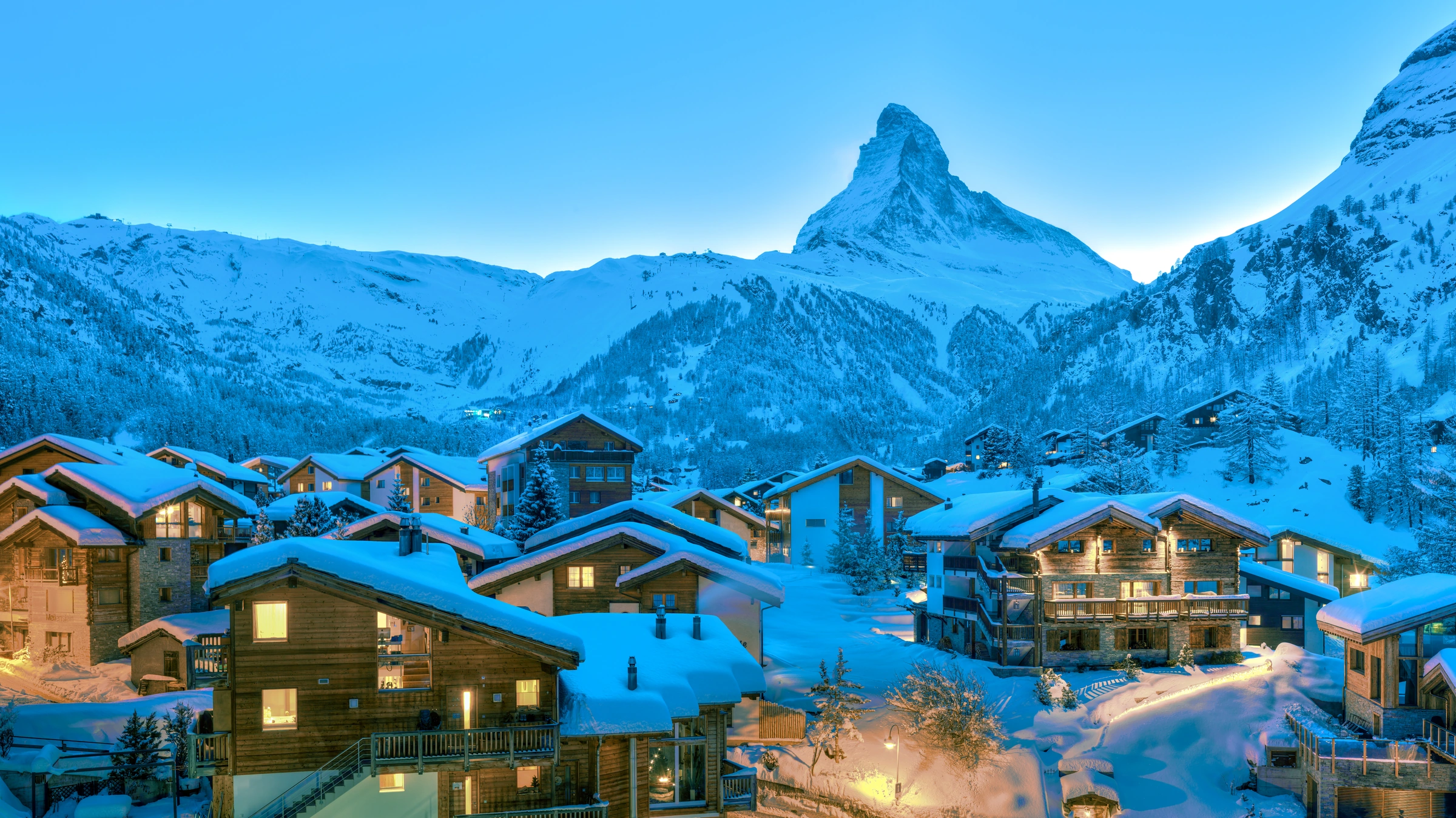 Snow-covered Zermatt chalets and the Matterhorn at blue hour.